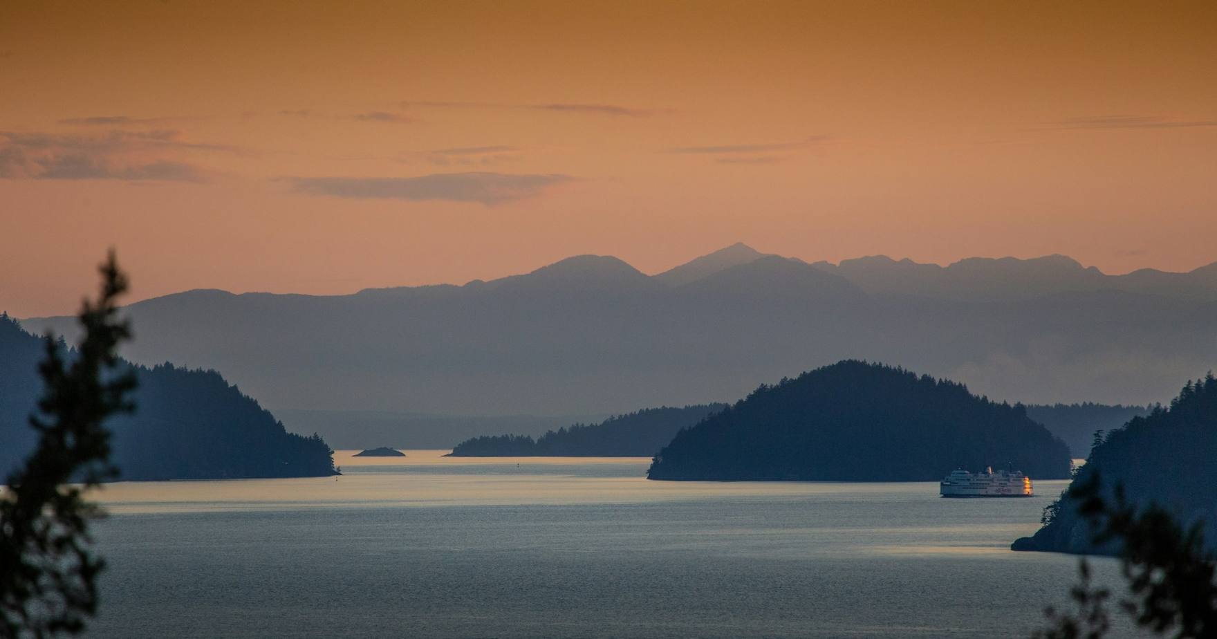 A BC Ferries vessel sailing between the Gulf Islands at sunset — a Vancouver Island courier route
